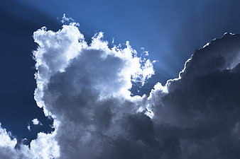 Dramatic white cumulus clouds against deep blue sky