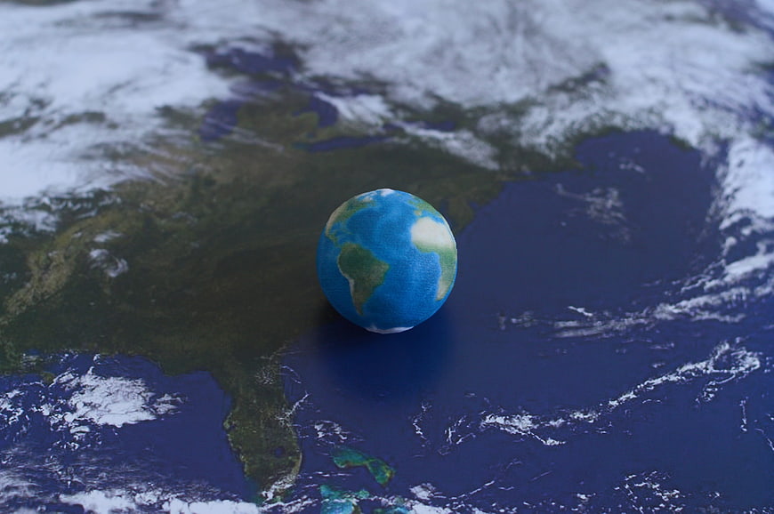 Small Earth Globe Model on Satellite Map Background