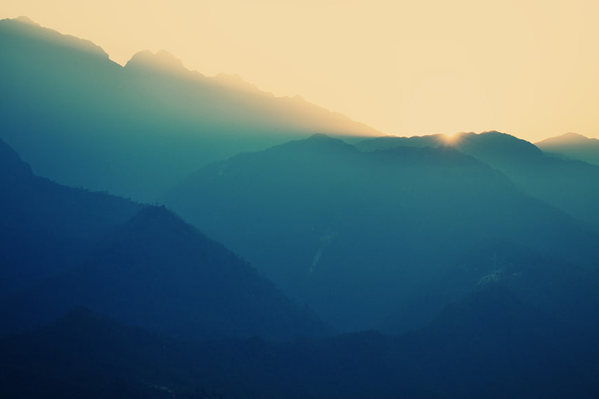 Misty Mountain Layers at Sunrise with Golden Sunlight