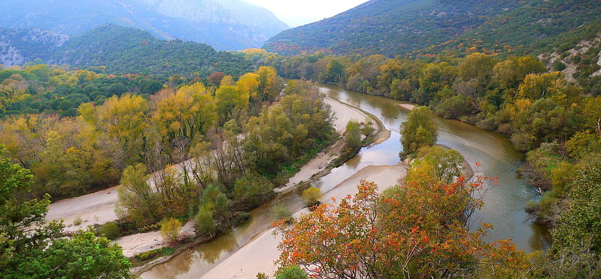 Panoramic autumn river valley with colorful forest and mountains