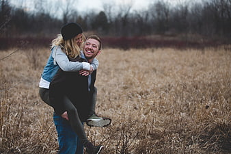 Happy couple piggyback ride in autumn field