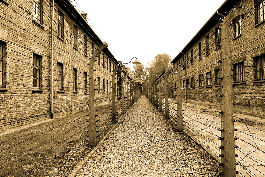 Sepia toned historical concentration camp barracks with barbed wire fence