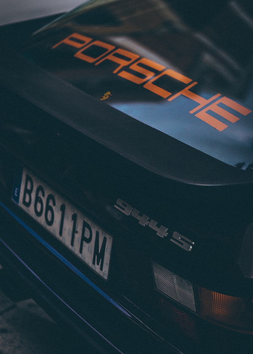 Close-up of black Porsche 944 S rear with orange decal
