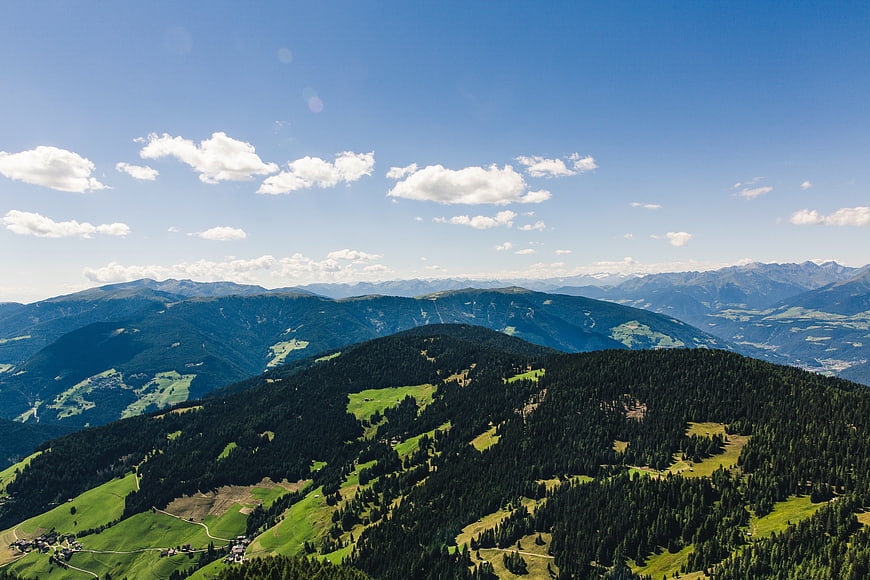 Panoramic Alpine Mountain Landscape with Green Forests and Blue Sky