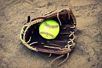 Softball in leather glove on dirt field