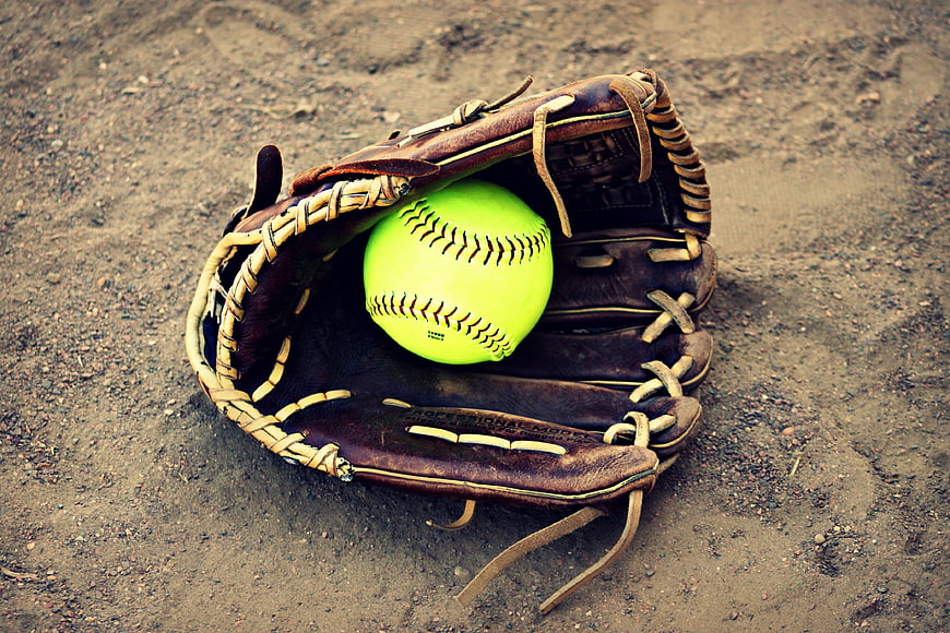 Softball in leather glove on dirt field