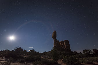 Night Sky with Moon Halo Over Desert Rock Formation