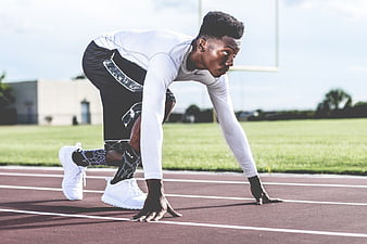 Athletic Man in Starting Position on Running Track