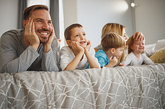Happy family lying on bed watching TV together