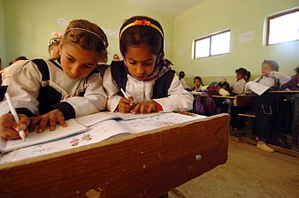 Two young girls studying together in a classroom