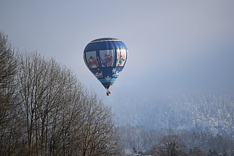 Blue Hot Air Balloon Flying Over Snowy Winter Forest