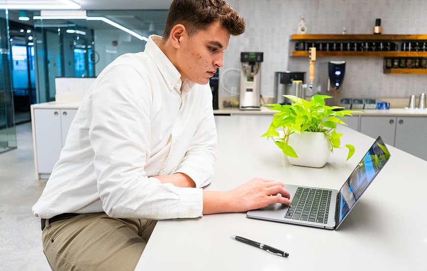 Young man working on laptop in modern office kitchen
