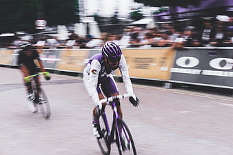 Cyclist in purple jersey racing on city street
