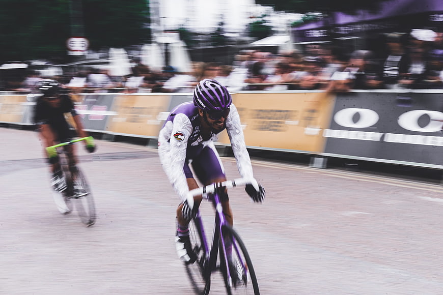 Cyclist in purple jersey racing on city street
