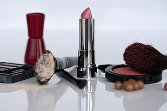 Pink lipstick and makeup brushes on white background