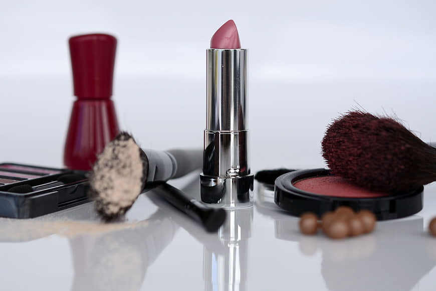 Pink lipstick and makeup brushes on white background