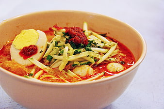 Bowl of spicy laksa noodles with egg and vegetables