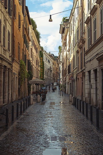 Wet cobblestone street in Rome with historic buildings