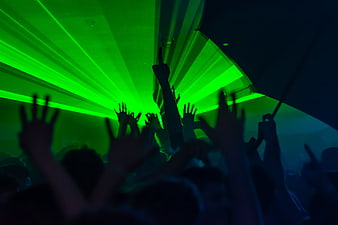 Silhouetted crowd with raised hands under green laser lights at a nightclub