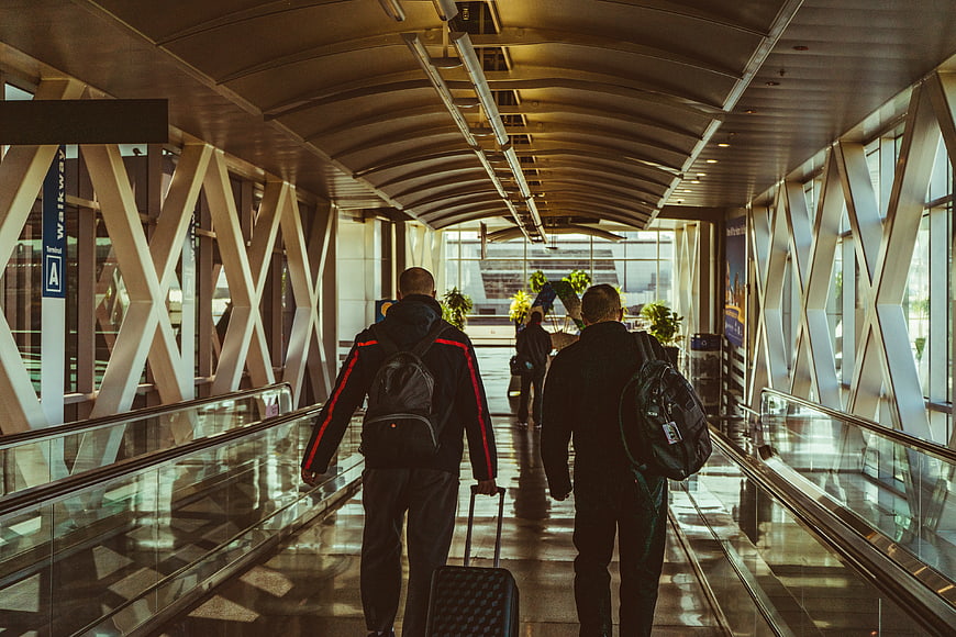 Travelers walking on moving walkway in modern airport terminal