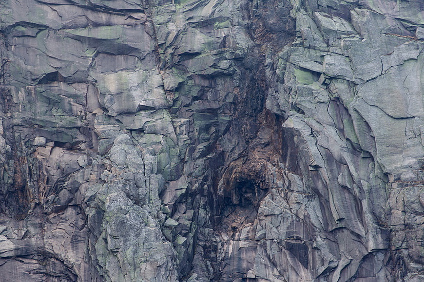 Textured Gray Rock Cliff Face with Green Lichen