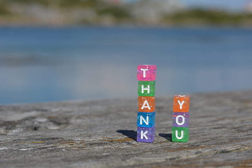 Colorful Beaded Letters Spelling Thank You on Weathered Wood