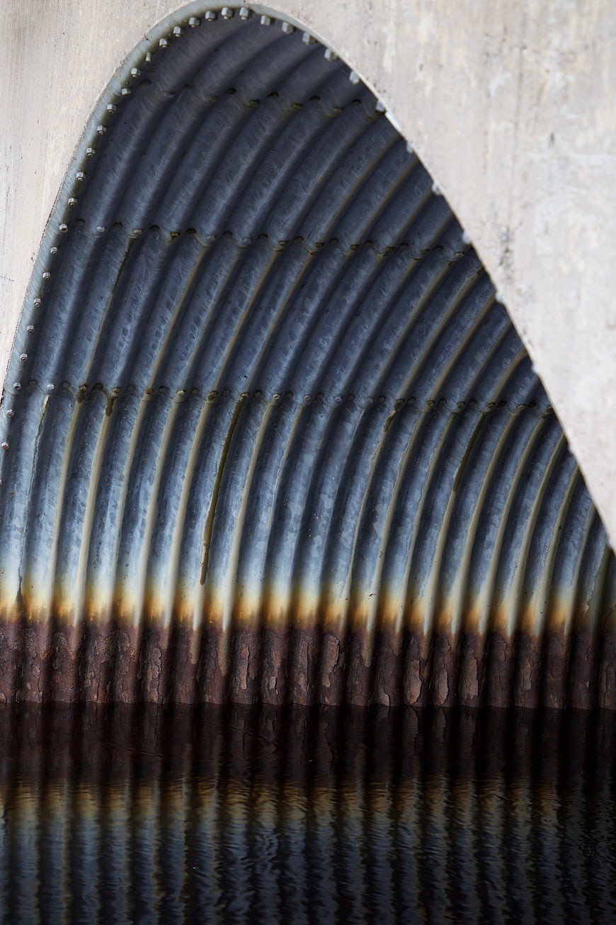 Abstract reflection of corrugated metal pipe in water