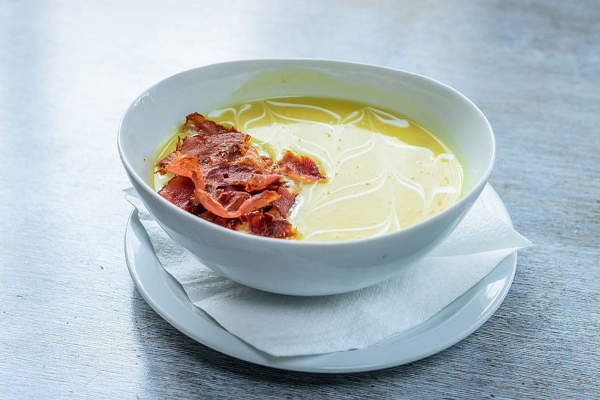Creamy soup with crispy bacon in a white bowl