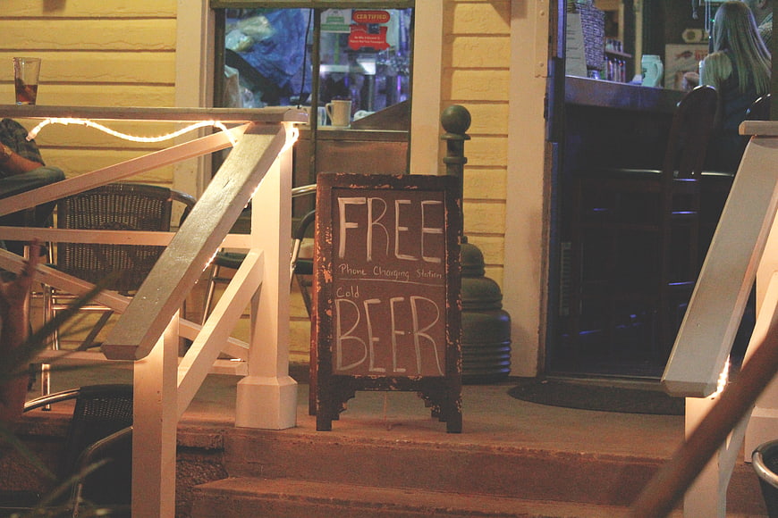 Chalkboard sign advertising free beer on porch steps