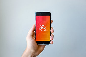 Hand holding smartphone with neon logo on screen