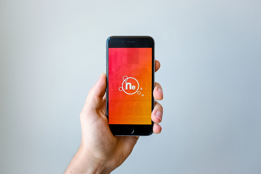 Hand holding smartphone with neon logo on screen