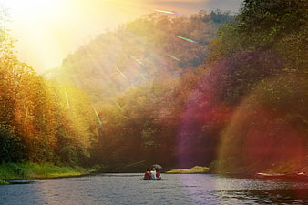 People in a boat on a river with dramatic sun flare