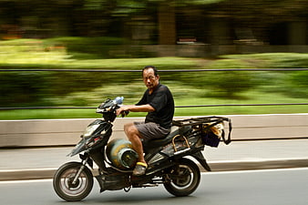 Man riding motorcycle with gas canister on road