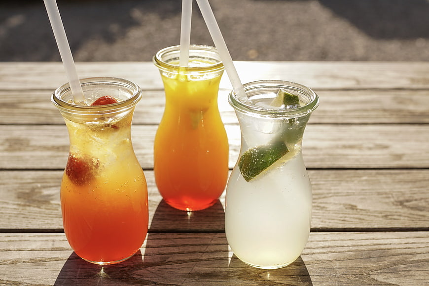 Three Refreshing Summer Lemonades In Glass Bottles On Wooden Table