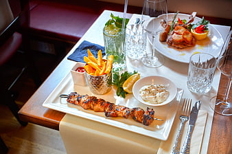 Restaurant Table Setting With Grilled Kebab, Fries, and Drinks