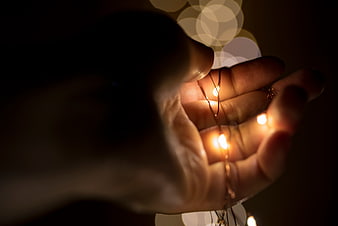 Hand holding warm fairy lights with bokeh background