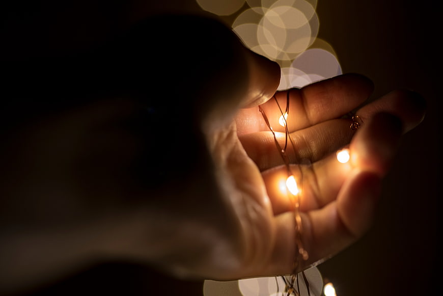Hand holding warm fairy lights with bokeh background