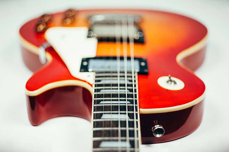 Close-up of a red sunburst electric guitar on white background