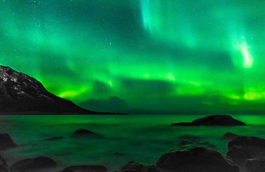 Vibrant Green Aurora Borealis Over Rocky Coastal Landscape