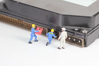 Miniature workers repairing a large computer hard drive