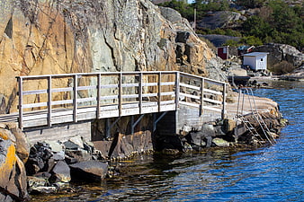 Wooden Bridge on Rocky Coastline by Blue Sea