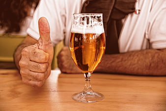 Man giving thumbs up next to a glass of beer
