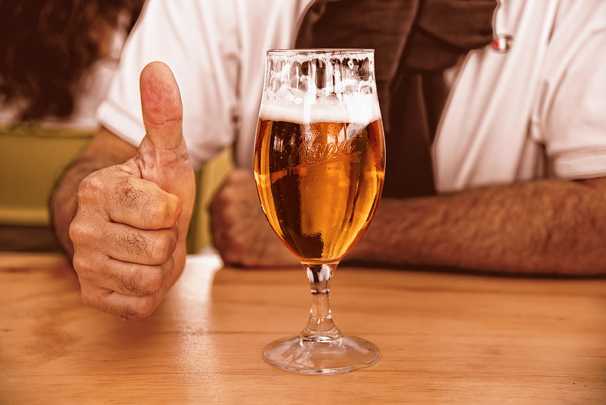 Man giving thumbs up next to a glass of beer
