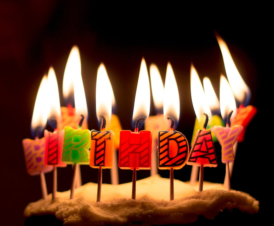 Lit Birthday Candles Spelling Happy Birthday on Cake