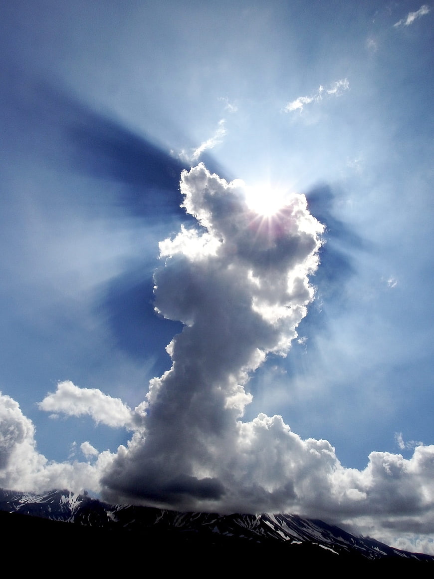 Dramatic Sun Rays Through Clouds Over Snowy Mountains