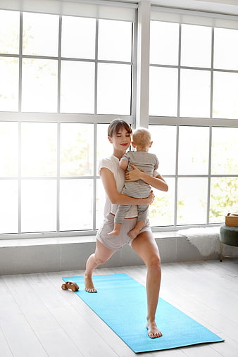 Mother doing yoga with baby in bright room
