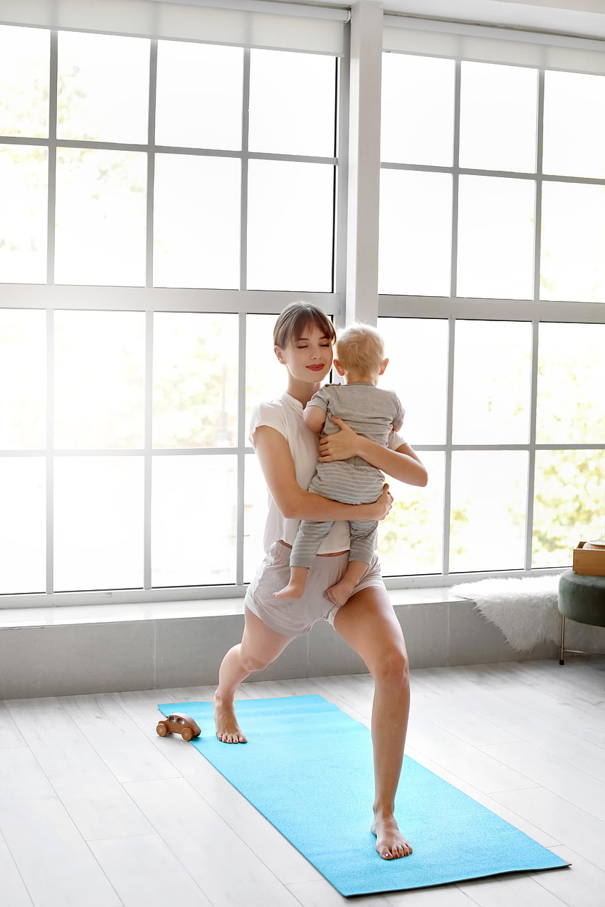 Mother doing yoga with baby in bright room