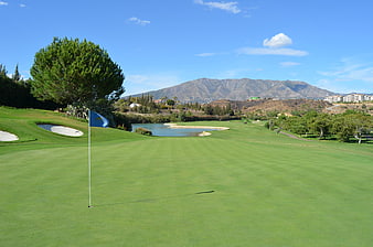 Golf Course Green With Flag, Water Hazard And Mountain View