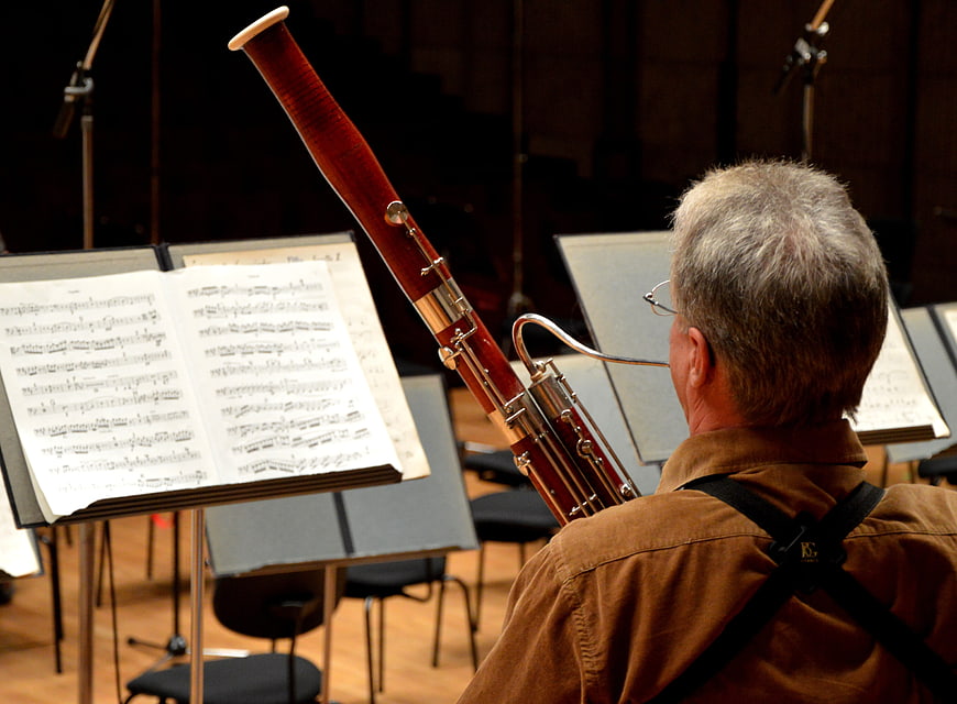 Senior bassoonist playing in orchestra with sheet music