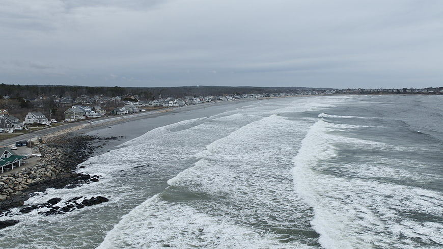 Aerial view of coastal town with waves crashing on overcast day